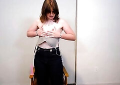 A smiling brunette hair shemale in a darksome blue tee and jeans teases the camera, then kneels on a leather chair to slip a pink sex tool into her bo